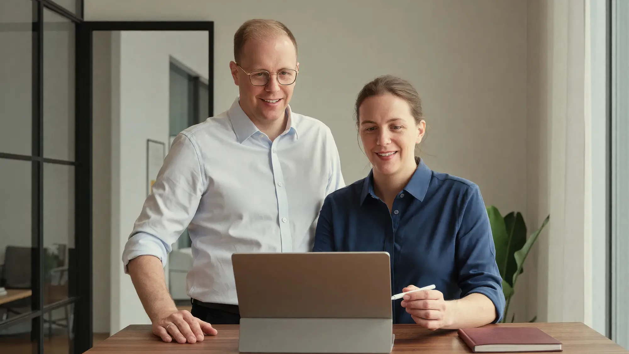 Tim Hoferichter im Austausch mit einer Mitarbeiterin an einem Laptop in den modernen Büroräumen von Hoferichter Unternehmenssteuerrecht.